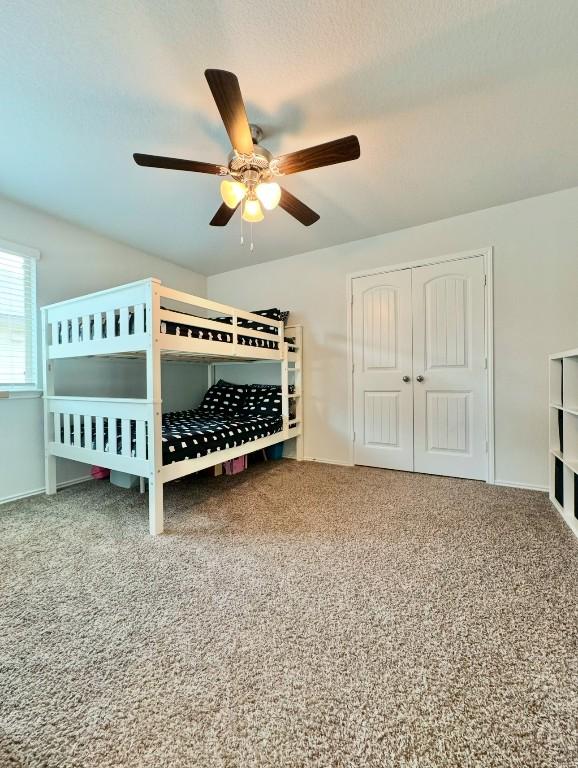 unfurnished bedroom with carpet flooring, ceiling fan, and a closet