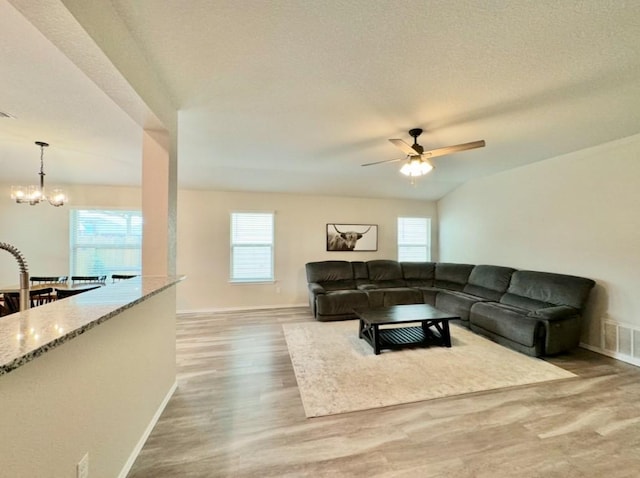 living room with hardwood / wood-style flooring, a healthy amount of sunlight, ceiling fan with notable chandelier, and a textured ceiling