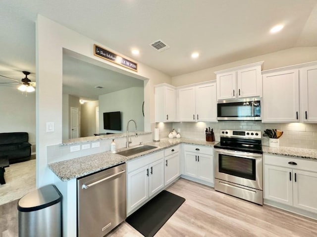 kitchen with stainless steel appliances, light stone countertops, sink, and white cabinets