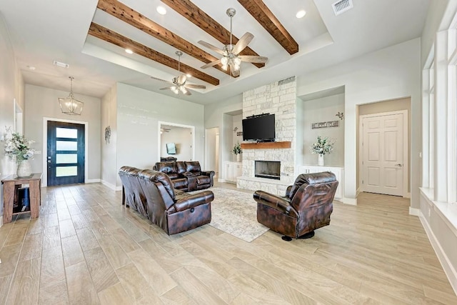 living room with a fireplace, beamed ceiling, ceiling fan with notable chandelier, and light wood-type flooring