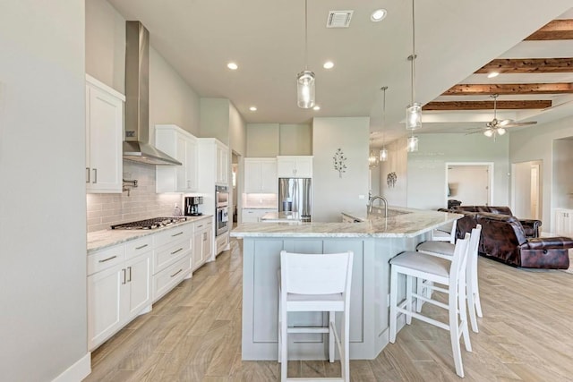 kitchen featuring beam ceiling, a large island, hanging light fixtures, white cabinets, and appliances with stainless steel finishes