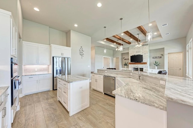 kitchen with white cabinets, ceiling fan, light wood-type flooring, a large island, and beam ceiling