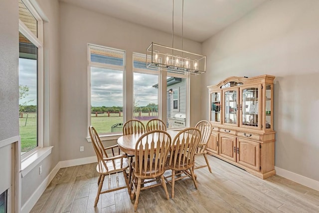 dining area with light hardwood / wood-style floors and a notable chandelier