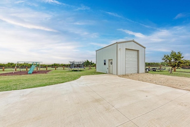 view of outdoor structure with a lawn, a trampoline, a garage, and a playground