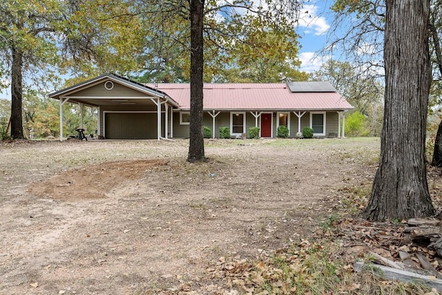 ranch-style home featuring a garage, a porch, and solar panels