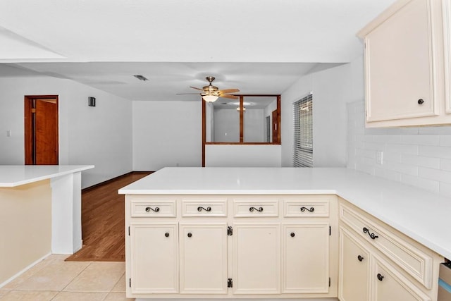 kitchen featuring ceiling fan, light hardwood / wood-style flooring, backsplash, kitchen peninsula, and cream cabinetry