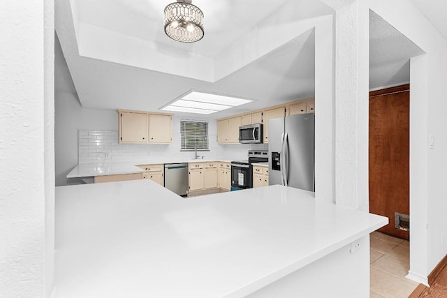 kitchen with sink, a notable chandelier, kitchen peninsula, light tile patterned flooring, and appliances with stainless steel finishes