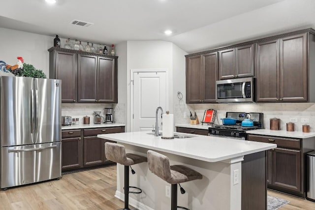 2912 Youngwood St, Leander, TX 78641 - kitchen with appliances with stainless steel finishes, tasteful backsplash, dark brown cabinets, light wood-style flooring, and light countertops