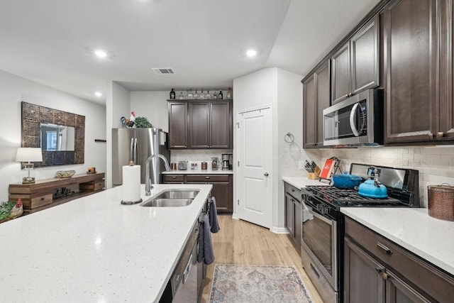 2912 Youngwood St, Leander, TX 78641 - kitchen featuring stainless steel appliances, dark brown cabinetry, tasteful backsplash, light stone counters, and light wood-style floors