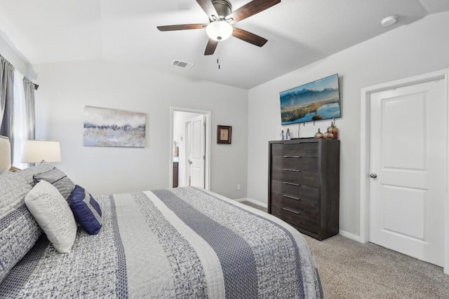 bedroom featuring ceiling fan, ensuite bathroom, light carpet, and vaulted ceiling