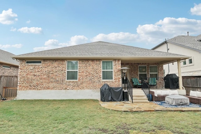 rear view of house featuring brick siding, a yard, roof with shingles, an outdoor hangout area, and fence
