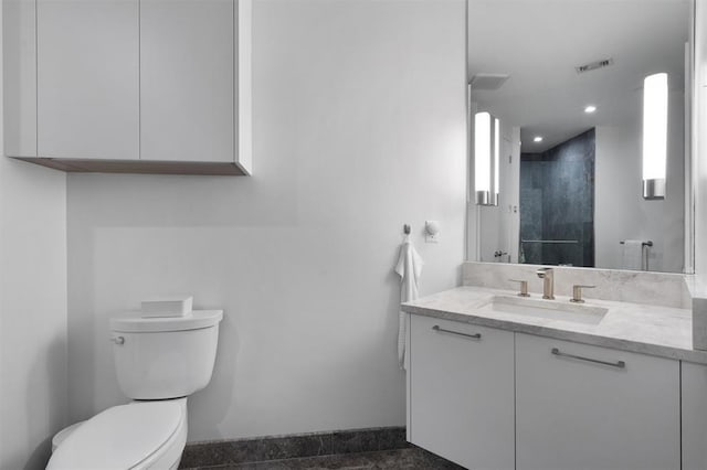 bathroom with toilet, vanity, and walk in shower