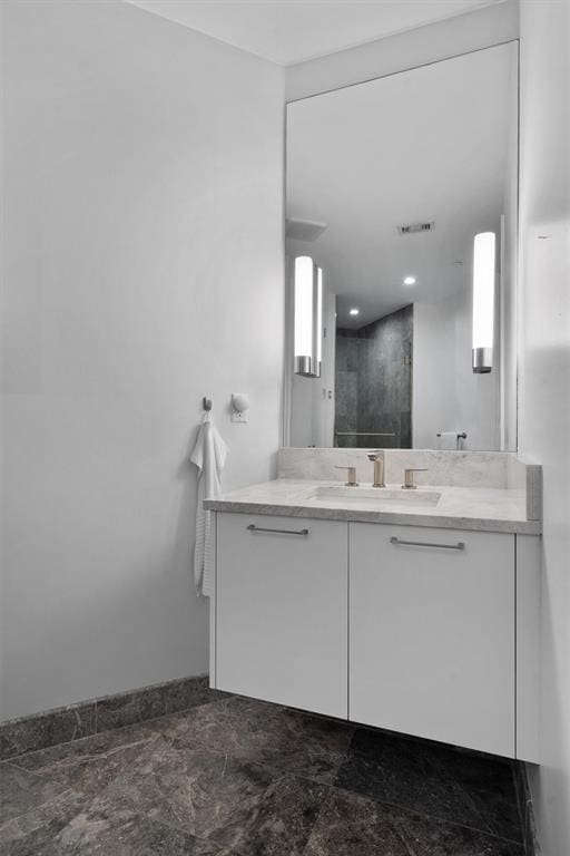 bathroom with a shower, vanity, and a healthy amount of sunlight