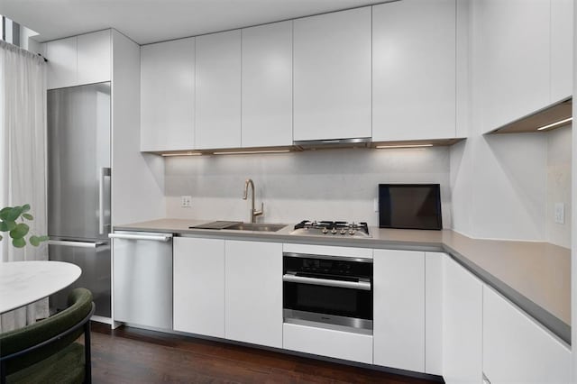 kitchen featuring sink, tasteful backsplash, dark hardwood / wood-style floors, white cabinets, and appliances with stainless steel finishes