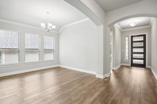 entryway featuring vaulted ceiling, wood-type flooring, ornamental molding, and a chandelier