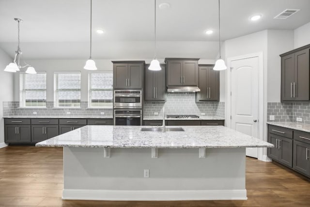 kitchen with a breakfast bar, decorative light fixtures, and an island with sink