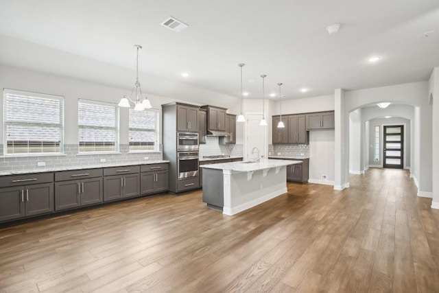 kitchen with a kitchen bar, a center island with sink, hanging light fixtures, and a notable chandelier