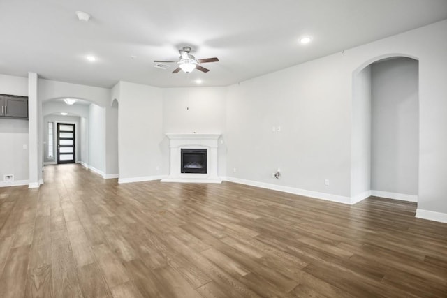 unfurnished living room featuring ceiling fan and dark wood-type flooring