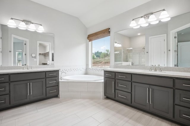 bathroom with tile patterned floors, vanity, vaulted ceiling, and shower with separate bathtub