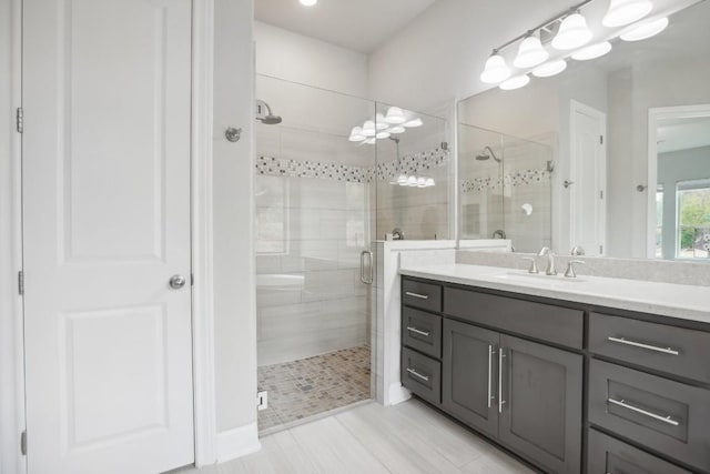 bathroom featuring a shower with door and vanity