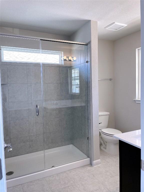 bathroom with tile patterned floors, vanity, toilet, and an enclosed shower