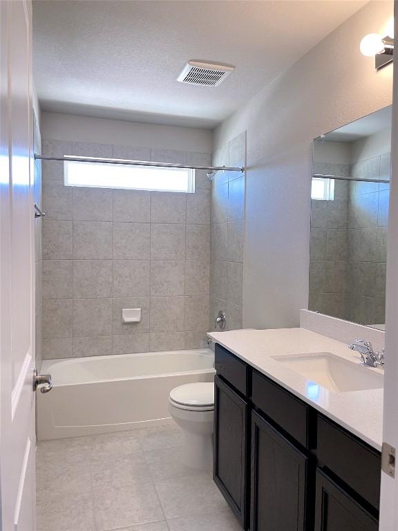 full bathroom featuring vanity, tiled shower / bath combo, and toilet