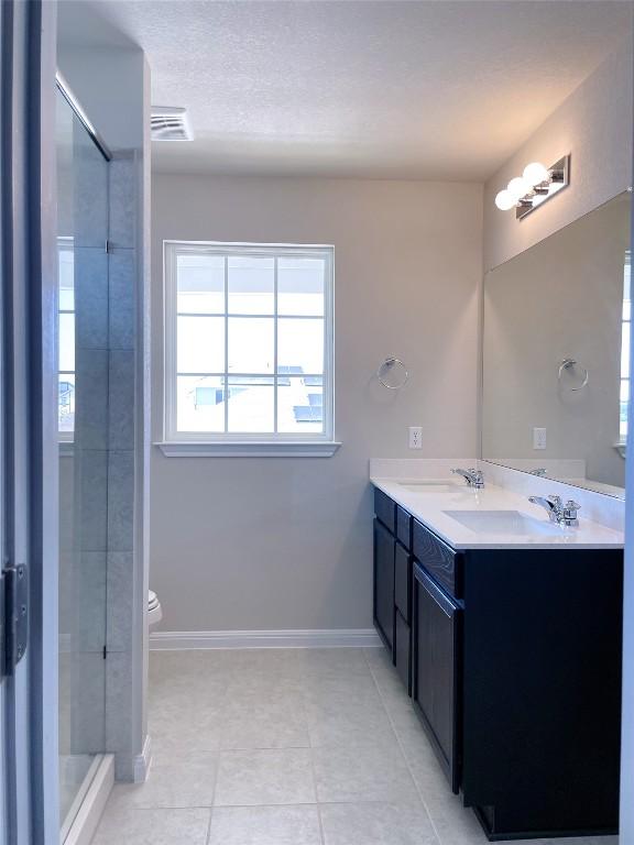 bathroom featuring tile patterned floors, vanity, tiled shower, and toilet