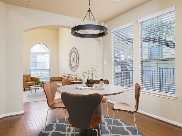 dining room with arched walkways, dark wood-style flooring, visible vents, and baseboards