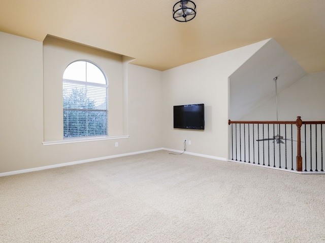 unfurnished living room with lofted ceiling, baseboards, and carpet flooring