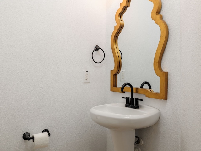 bathroom featuring a textured wall and a sink