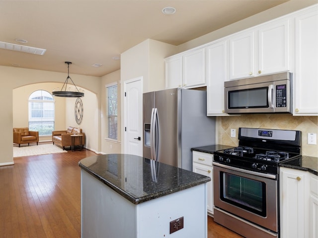 kitchen featuring appliances with stainless steel finishes, a center island, white cabinets, and decorative light fixtures