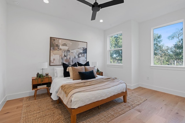 bedroom featuring multiple windows, light hardwood / wood-style floors, and ceiling fan