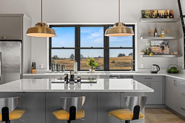 kitchen featuring a breakfast bar, gray cabinets, light stone countertops, and hanging light fixtures