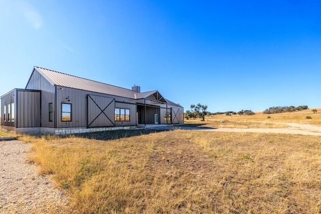 rear view of property with a rural view, an outbuilding, and a yard