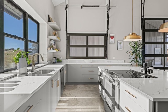 kitchen with gray cabinetry, light stone countertops, sink, hanging light fixtures, and stainless steel appliances