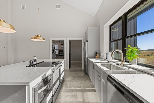 kitchen with pendant lighting, high vaulted ceiling, sink, light stone countertops, and appliances with stainless steel finishes