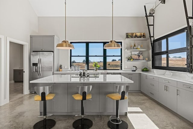 kitchen featuring a kitchen bar, stainless steel refrigerator with ice dispenser, a kitchen island, and gray cabinetry