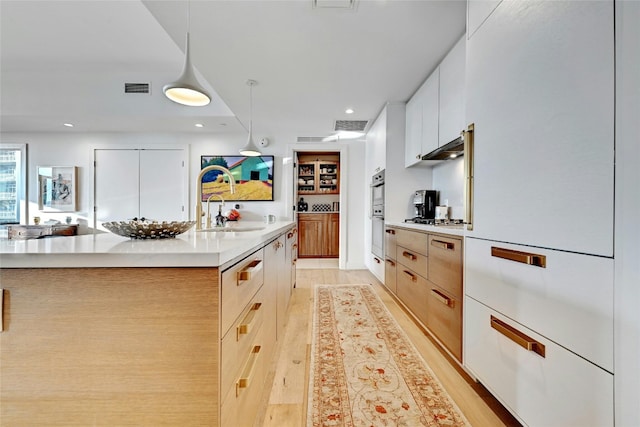 70 Rainey St Unit 1306, Austin, TX 78701 - kitchen with modern cabinets, light countertops, recessed lighting, a sink, and an island with sink