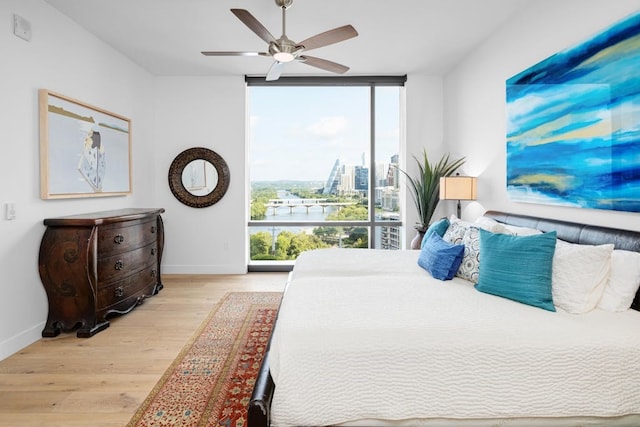 70 Rainey St Unit 1306, Austin, TX 78701 - bedroom with a wall of windows, baseboards, wood finished floors, and ceiling fan