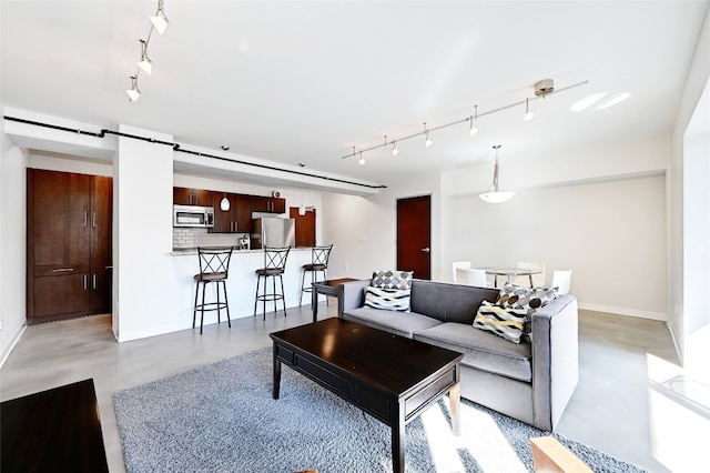 living area with baseboards, a barn door, track lighting, and finished concrete floors