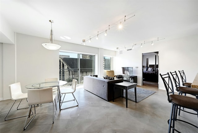 living area featuring rail lighting, baseboards, and concrete flooring