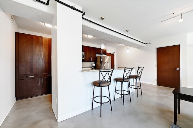 kitchen featuring a kitchen bar, decorative light fixtures, stainless steel fridge, kitchen peninsula, and a barn door