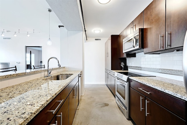 kitchen featuring stainless steel appliances, decorative light fixtures, light stone countertops, and sink