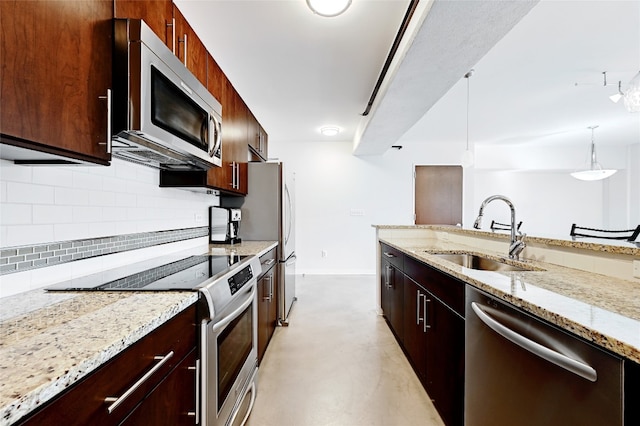 kitchen featuring appliances with stainless steel finishes, decorative light fixtures, light stone countertops, and sink