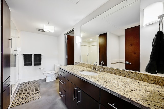 bathroom featuring a shower with door, vanity, and toilet