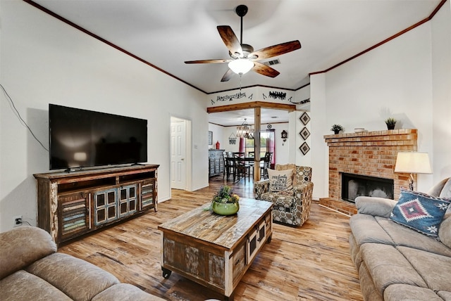 living room with a fireplace, ceiling fan with notable chandelier, light hardwood / wood-style floors, and crown molding