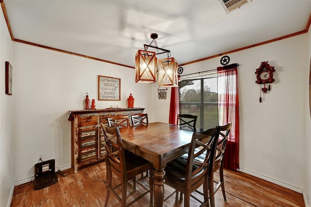 dining space featuring hardwood / wood-style floors and crown molding