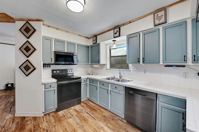 kitchen with decorative backsplash, appliances with stainless steel finishes, a textured ceiling, sink, and light hardwood / wood-style flooring