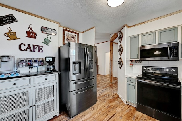 kitchen featuring decorative backsplash, stainless steel appliances, a textured ceiling, and light wood-type flooring