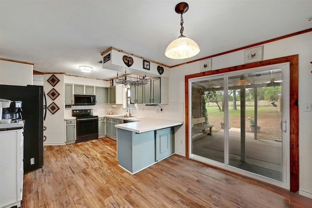 kitchen with pendant lighting, black appliances, light wood-type flooring, and sink